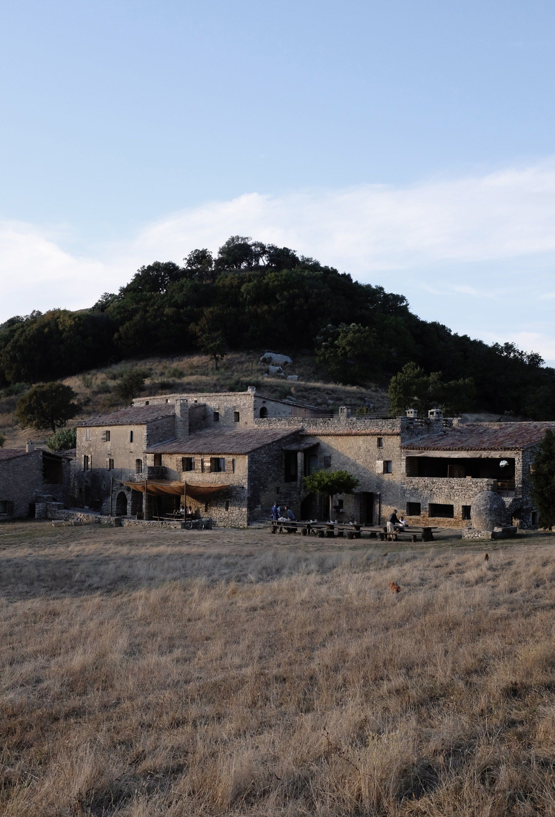 A stone village on a hillside above a field
