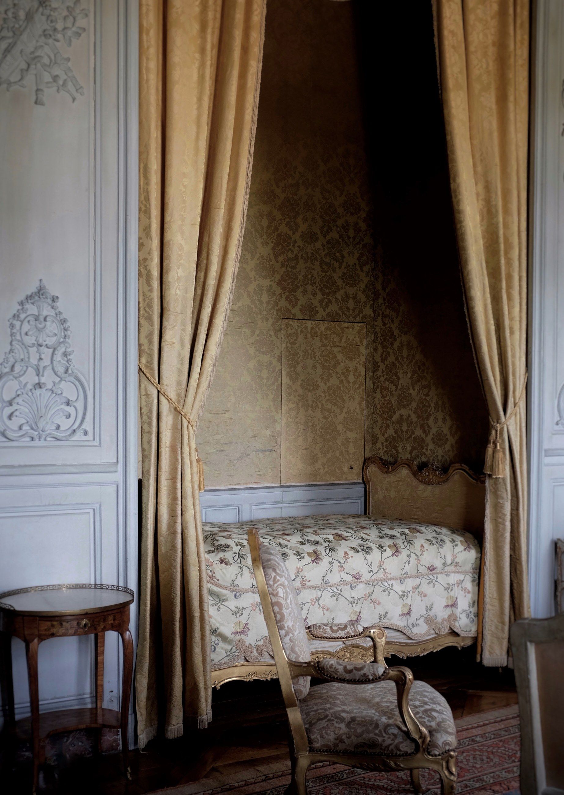 A canopy bed with gold curtains in a château bedroom