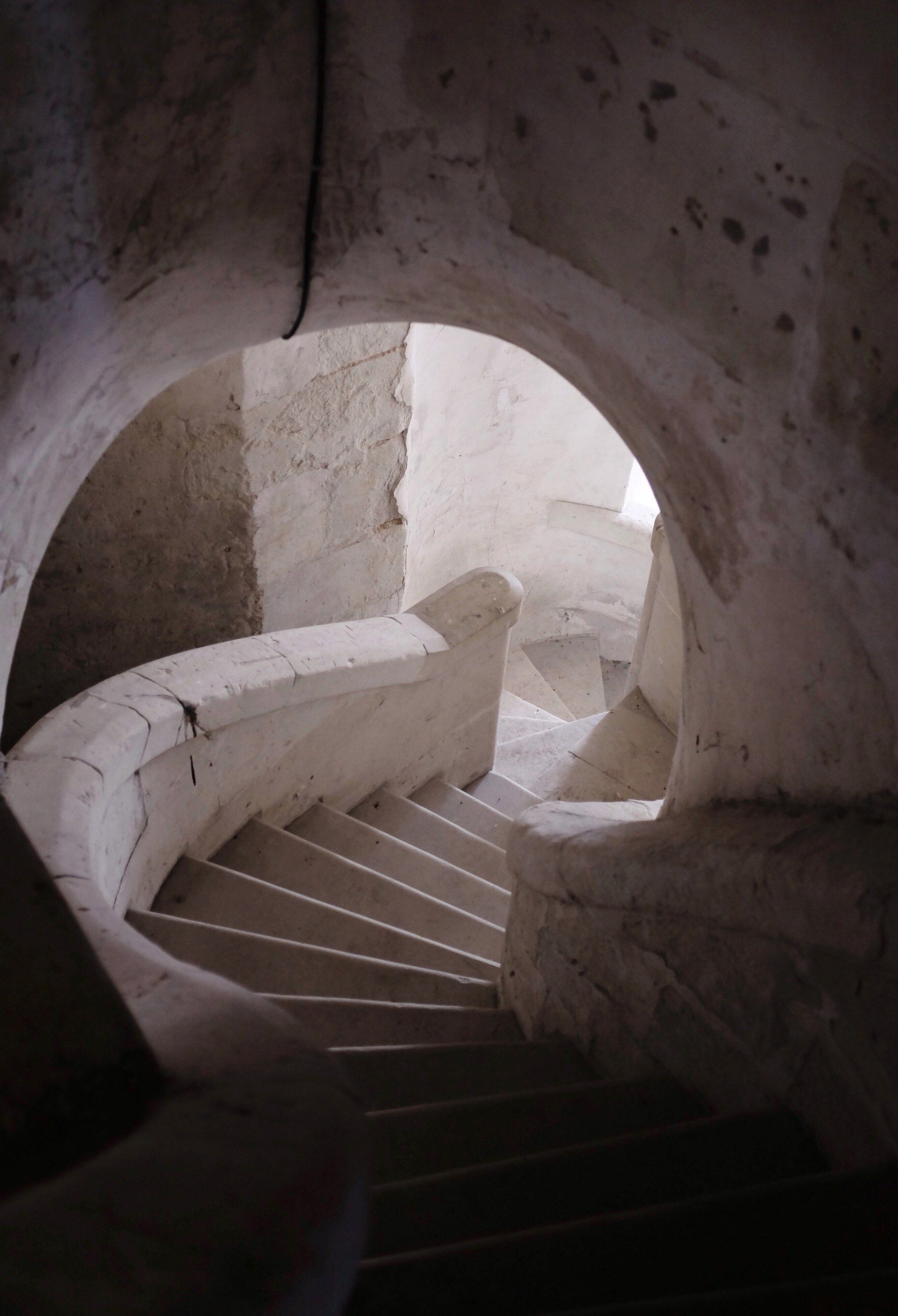 A stone spiral staircase lit from a round window