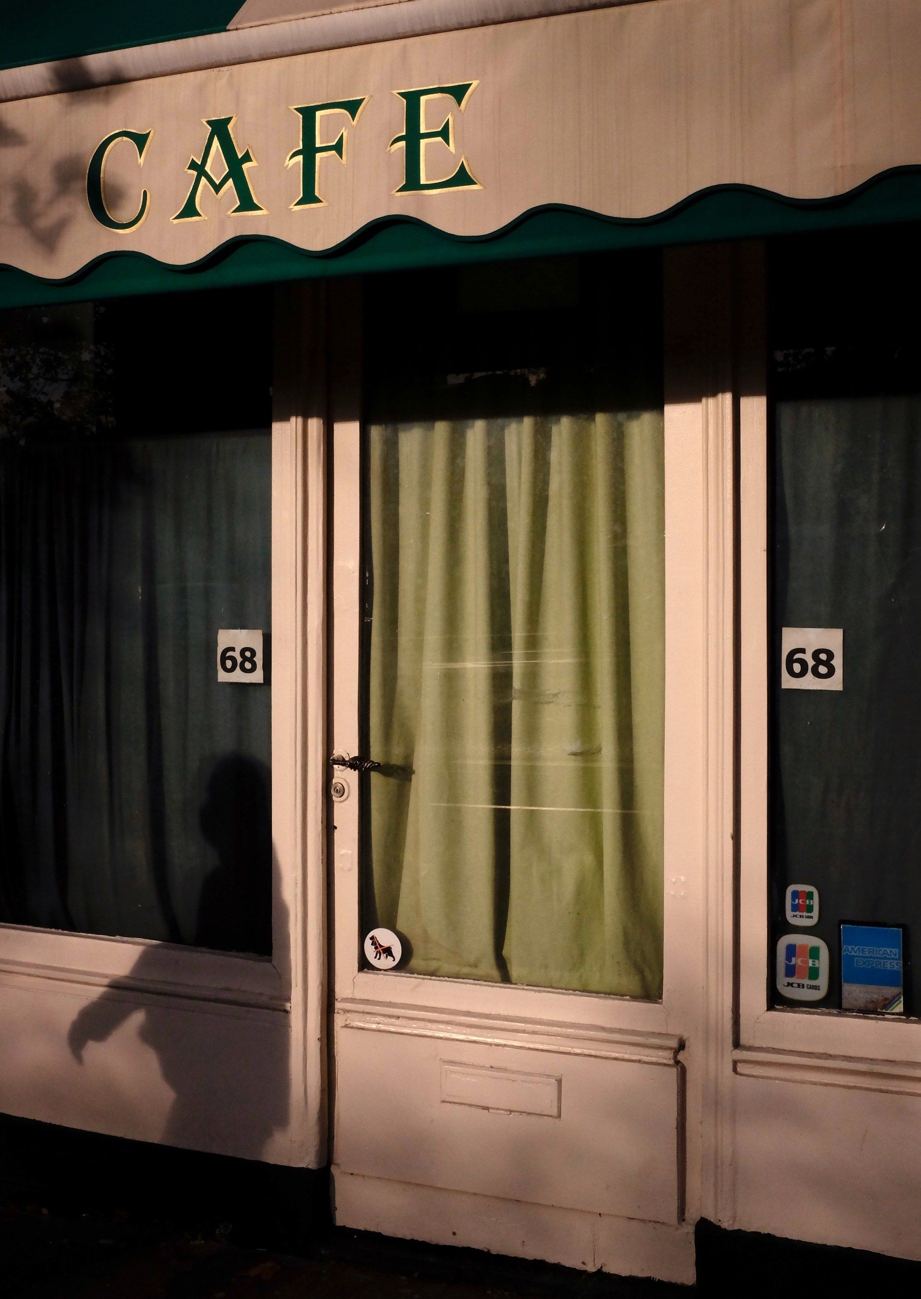 A Paris café front with a scalloped awning and green curtains