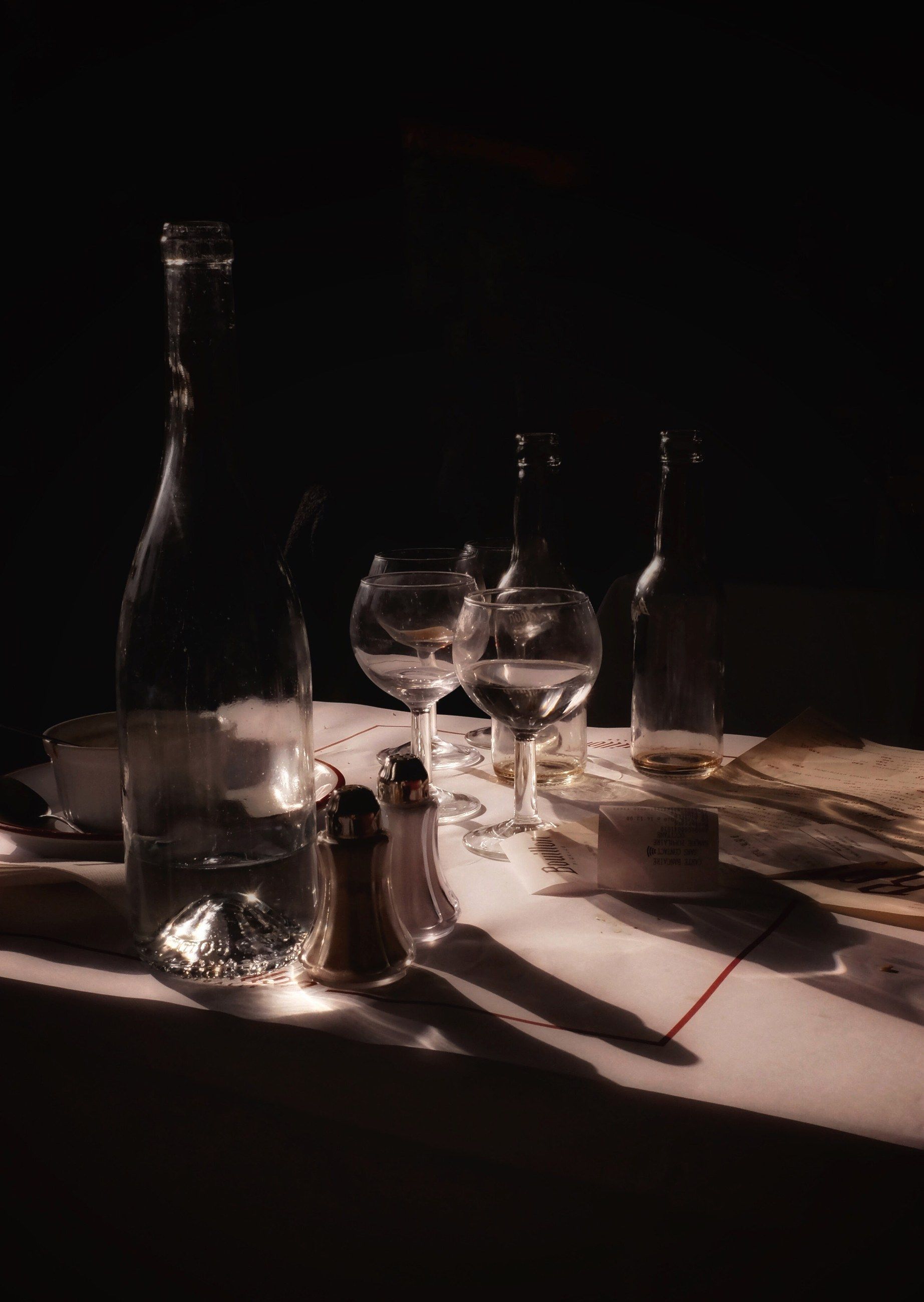 Wine glasses and a bottle on a table in low sunlight
